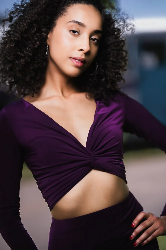 Senior portrait session in Connecticut featuring a graduate in a purple dress posing outdoors on a bridge in natural light.