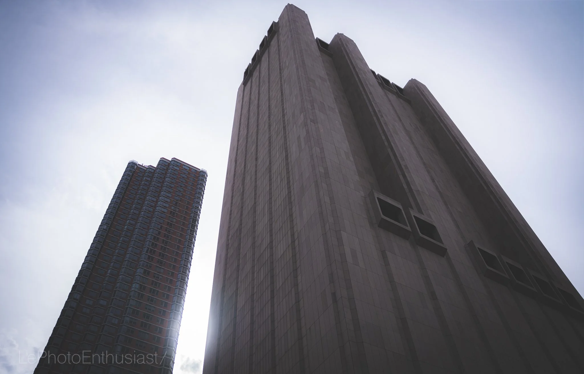 Low-angle view of tall skyscraper buildings against a cloudy sky.