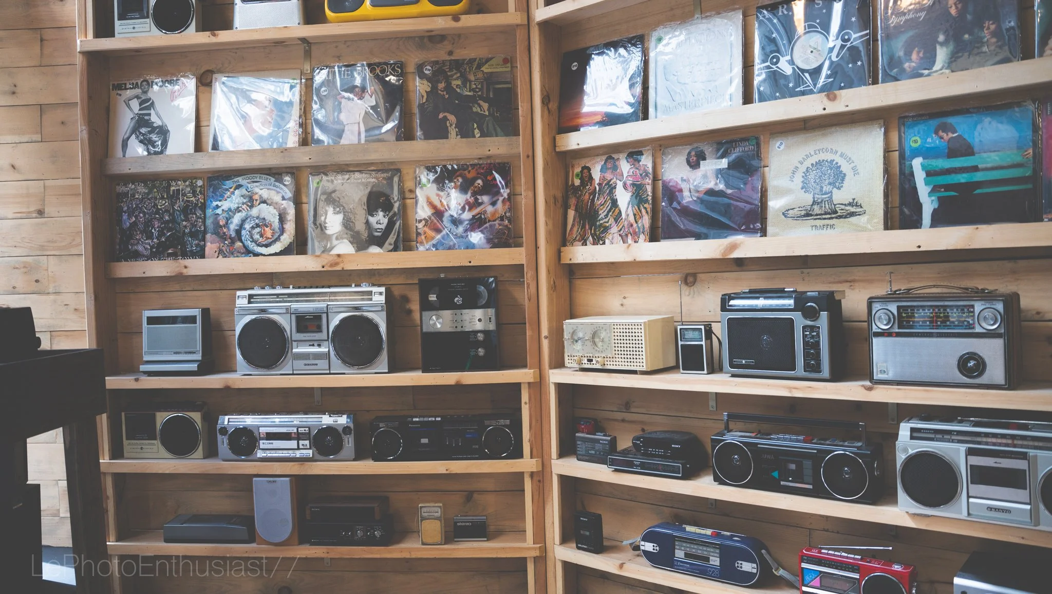 Wooden shelves filled with vintage vinyl records and old radios and stereo systems.