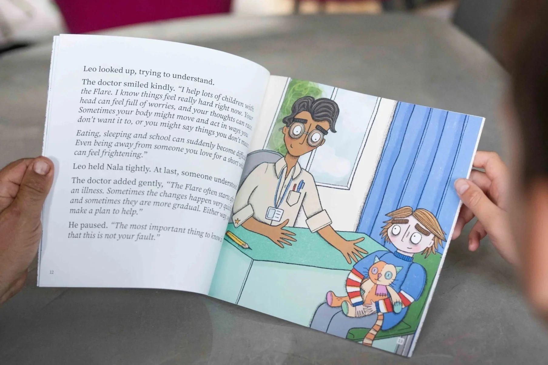 An open children's book The Flare: A Story About PANS PANDAS and Ways To Cope showing an illustration of a doctor and a young girl sitting in a room with a window, accompanied by text discussing feelings and health.