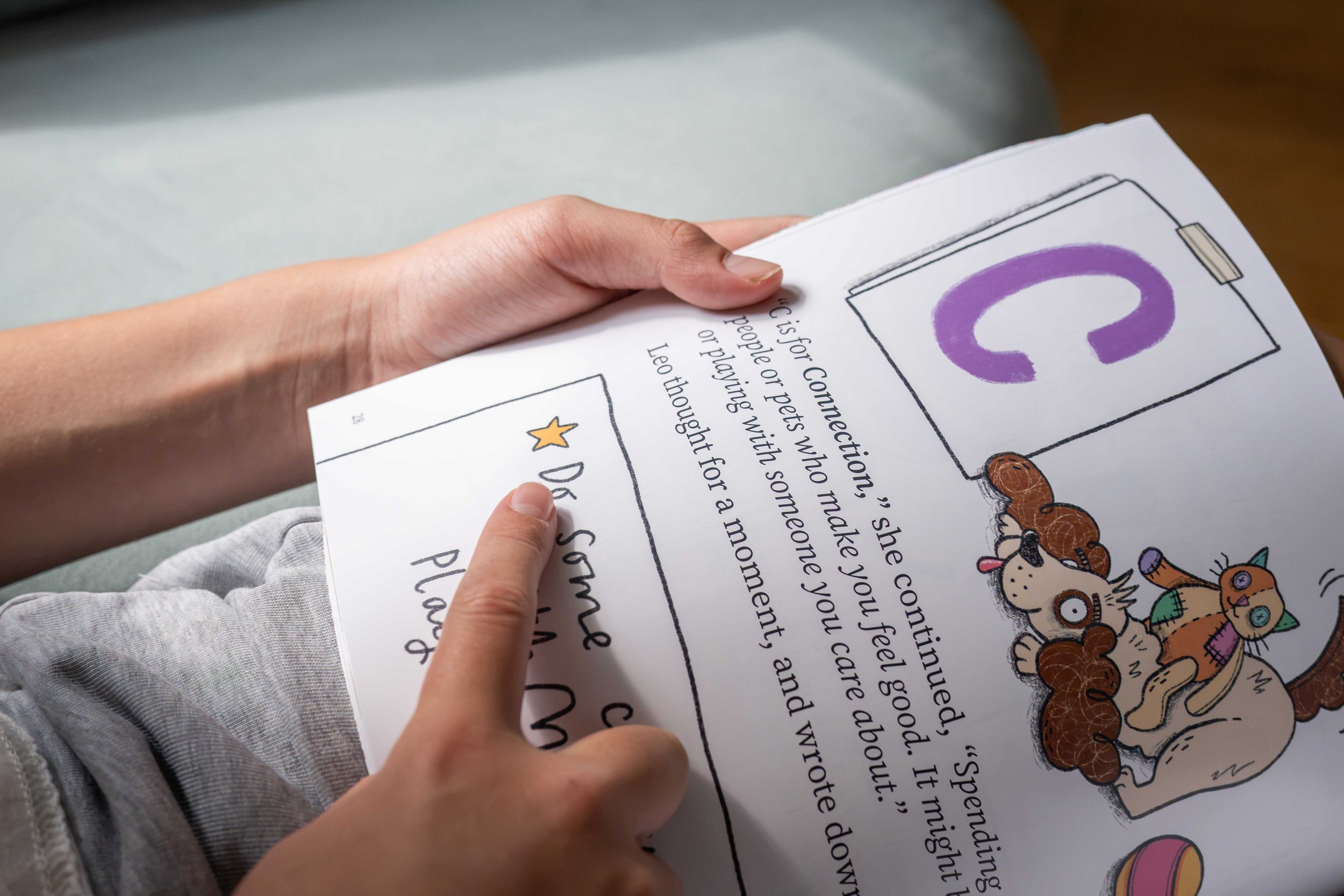 A person holding a colorful illustrated page of the book The Flare: A Story About PANS PANDAS and Ways To Cope
