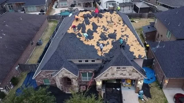 People working on replacing roof shingles on a house, exposing the roof deck