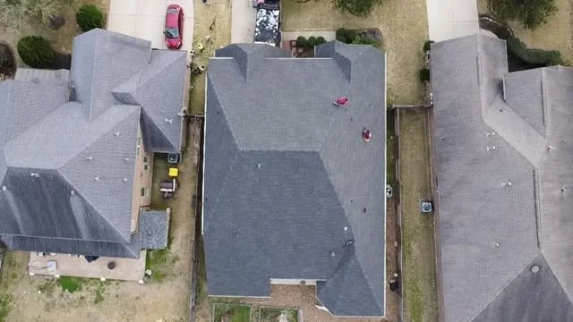 Aerial view of three neighboring houses with gray roofs, driveways, and small front yards.