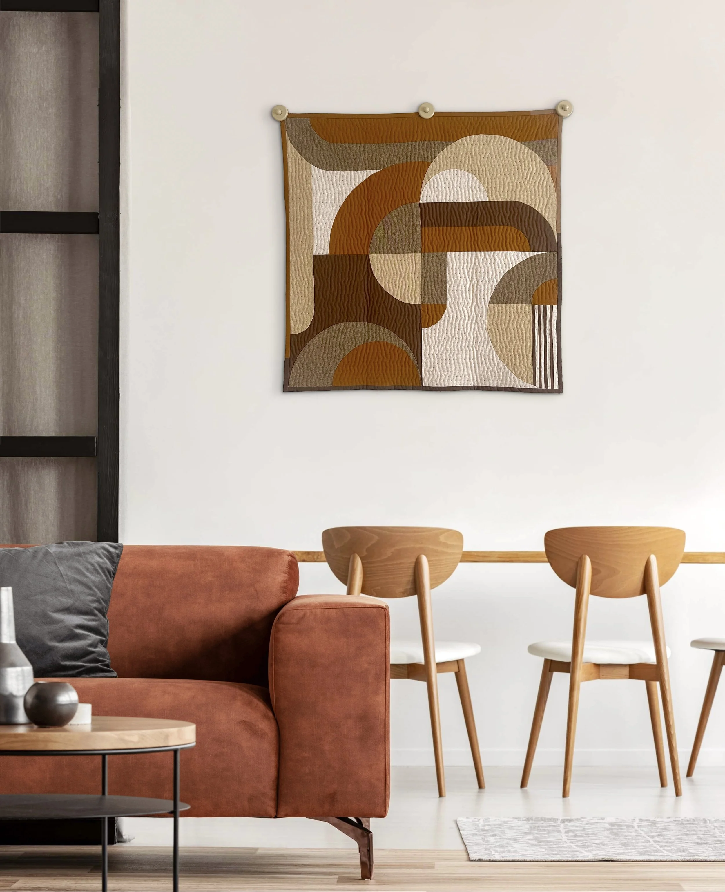 Living room with a rust-colored sofa, black coffee table, and a wooden dining table with four matching chairs. Abstract geometric art hangs on the white wall, and a small rug is on the light wood floor.
