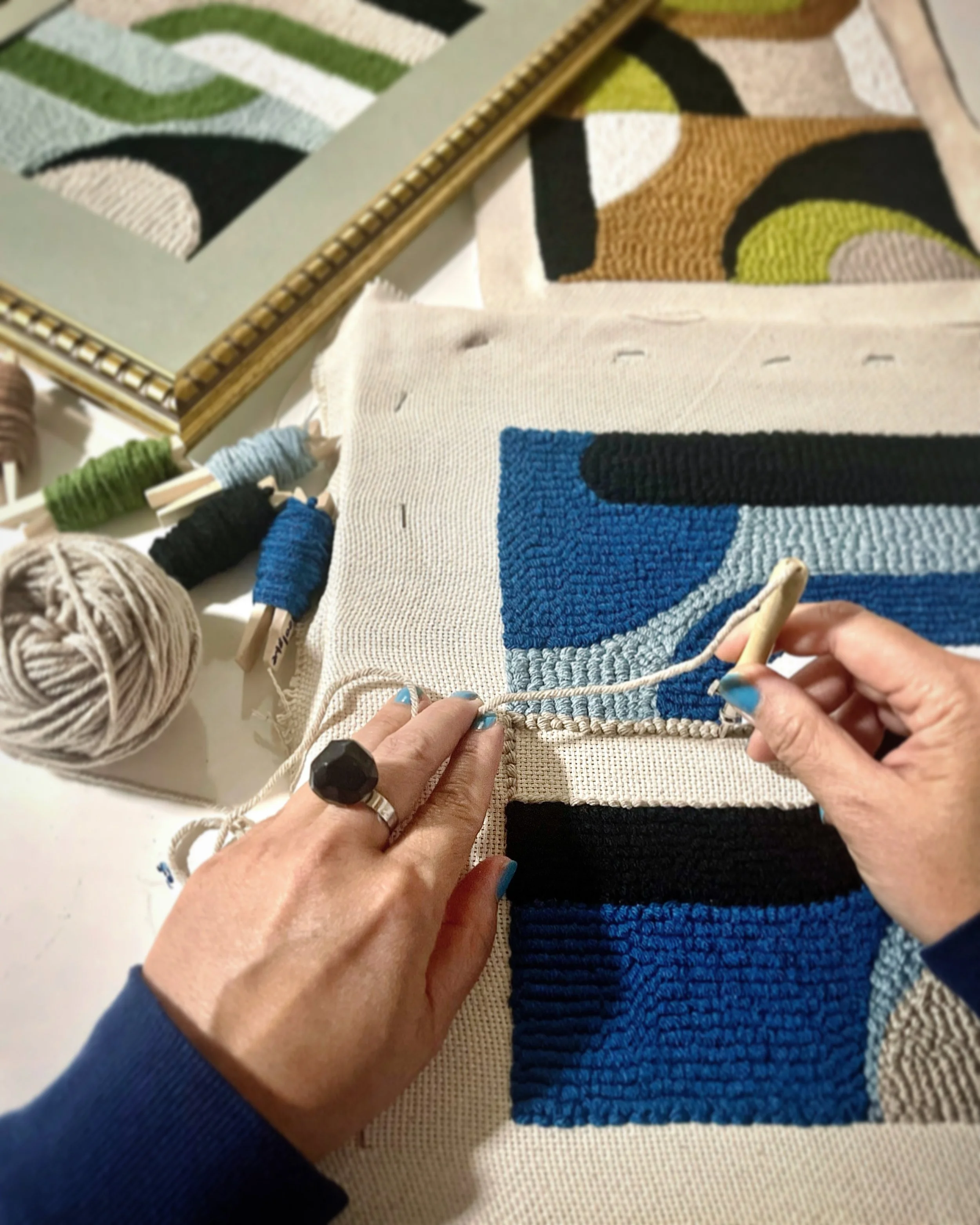 Person knitting colorful geometric pattern on fabric with yarn and knitting needles.