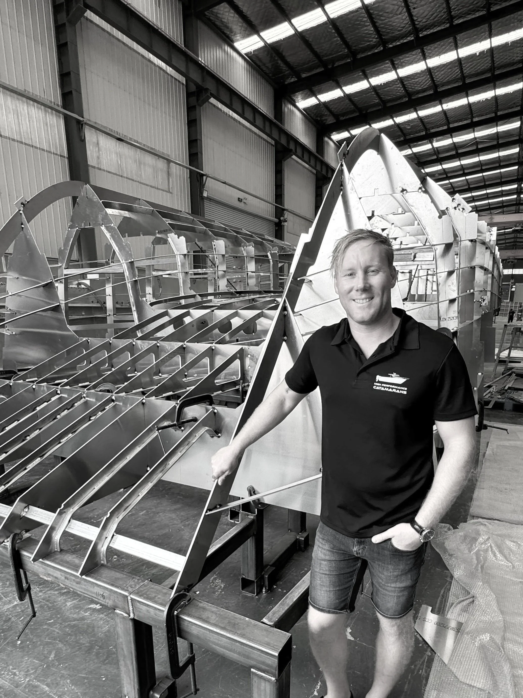 The boat builder standing next to a hull being built