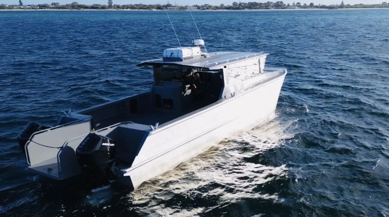 A large fishing or recreational boat named Crustacean II docked at a marina under a clear blue sky, with other boats and marina buildings in the background.