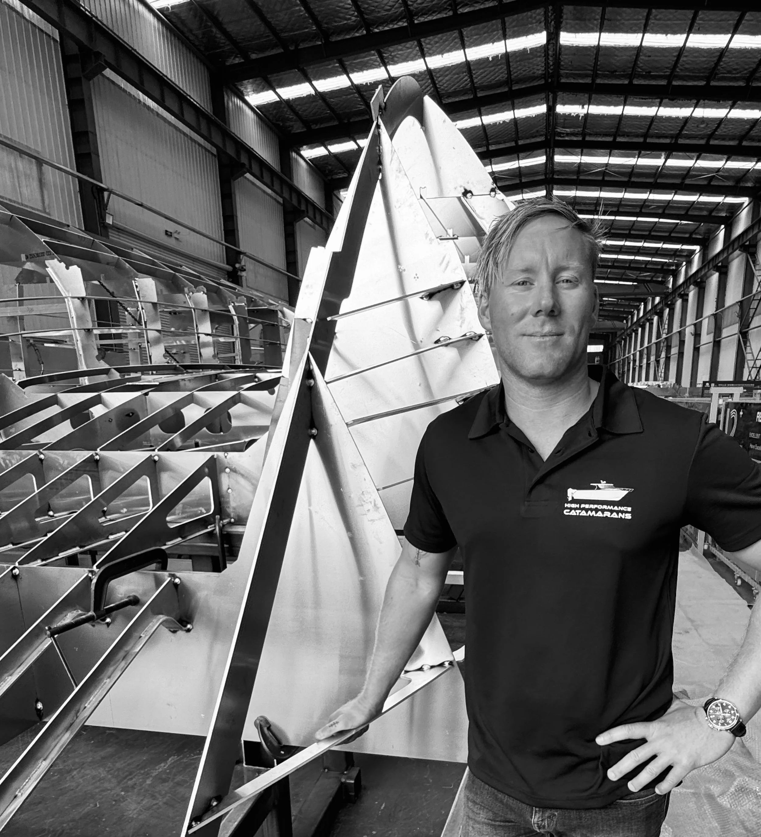 A boat builder in front of a commercial boat being built