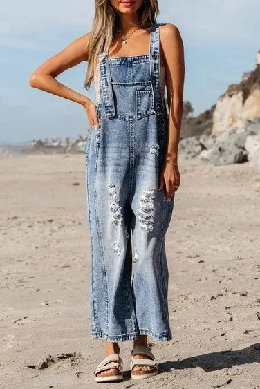 Woman wearing distressed denim overalls on a beach