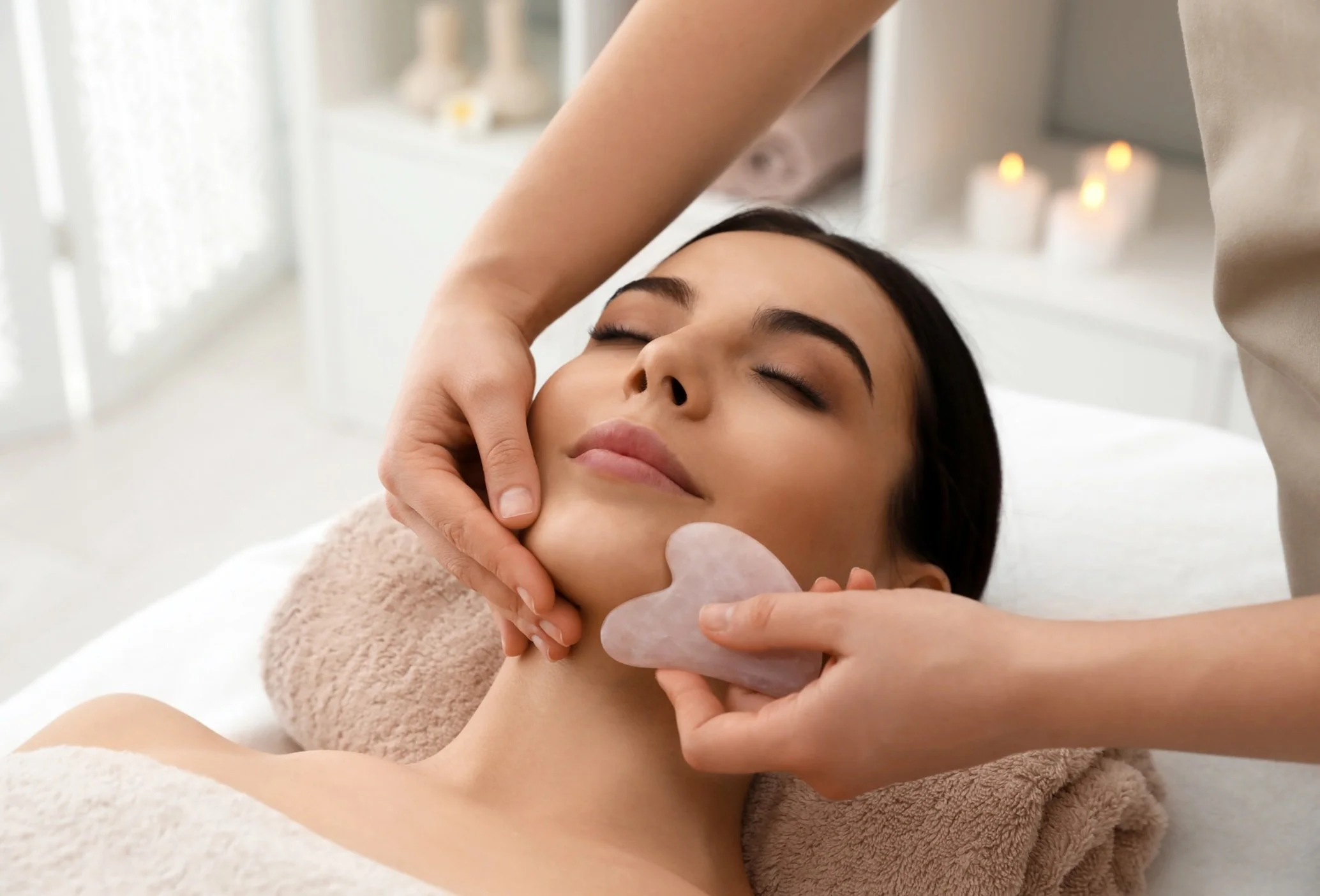 Woman receiving a facial treatment with a jade roller
