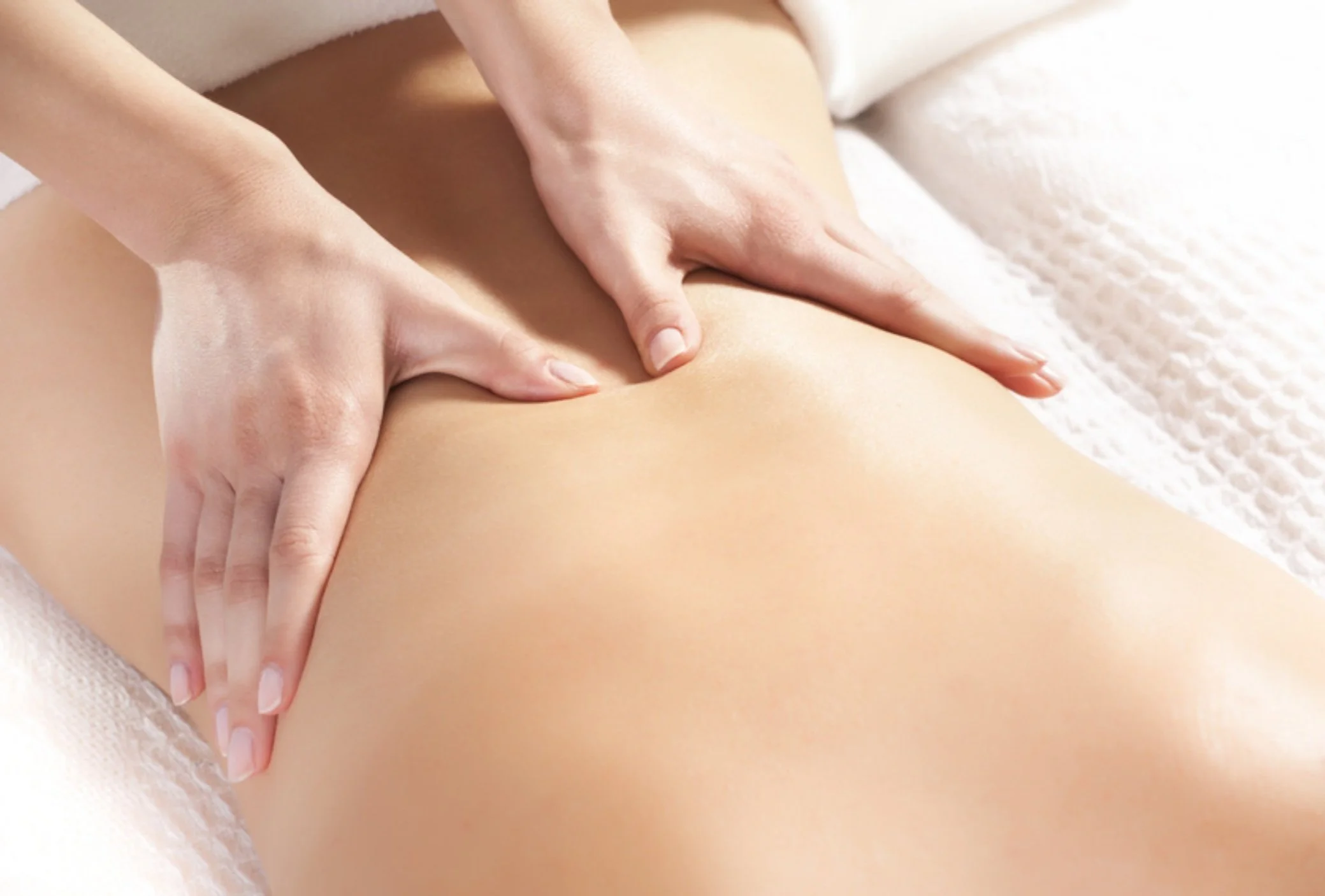 Person receiving a massage on their back and buttocks with professional massage therapist's hands