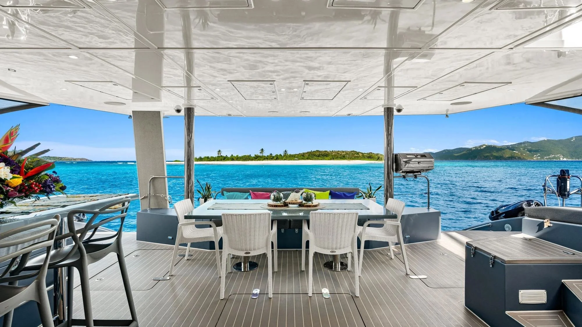 Aft-deck dining table aboard MAVERICK, a Sunreef 70 catamaran, anchored off a beach in the British Virgin Islands