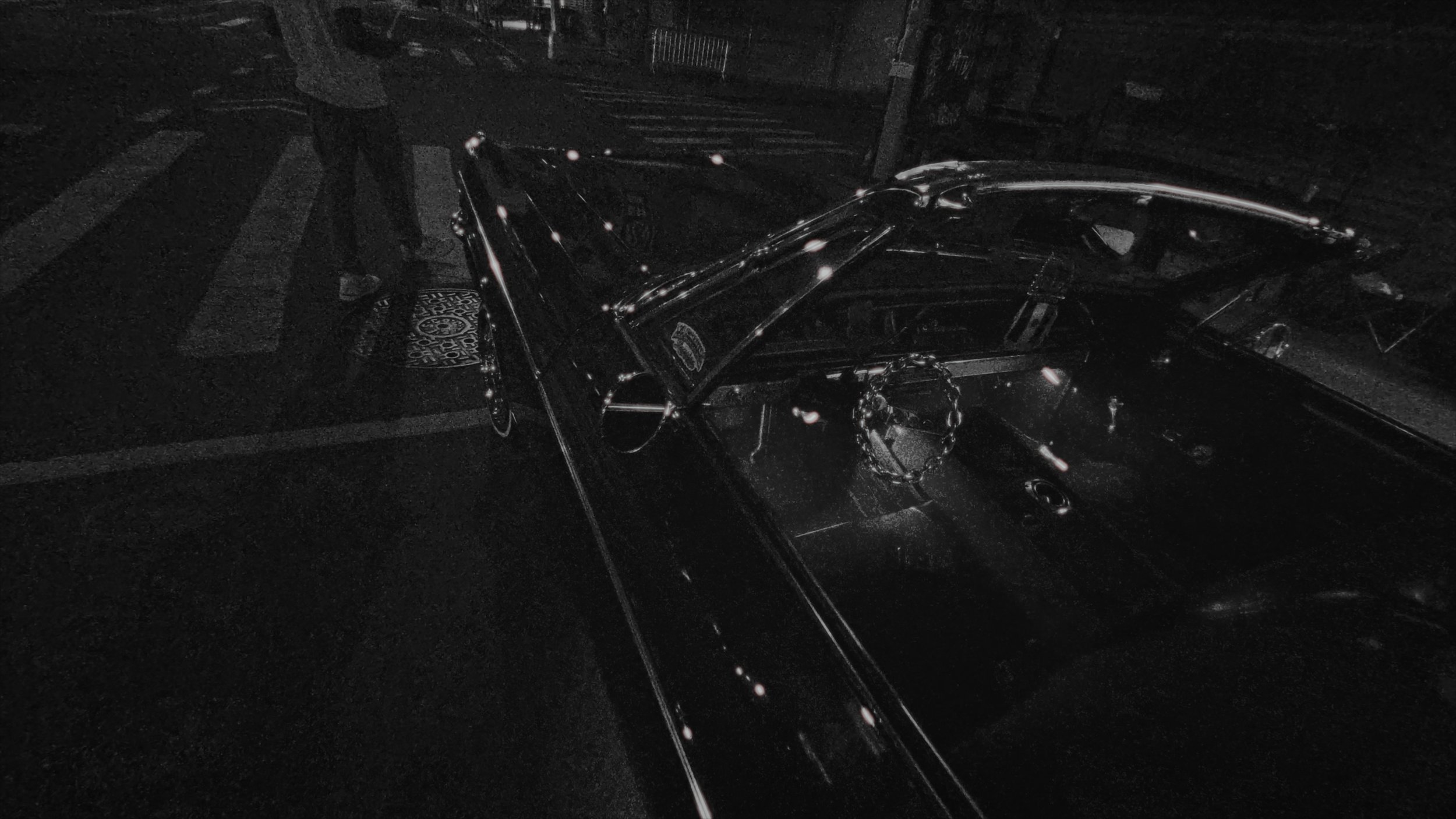 A black motorcycle parked on a street at night, with a person standing nearby, illuminated by streetlights.