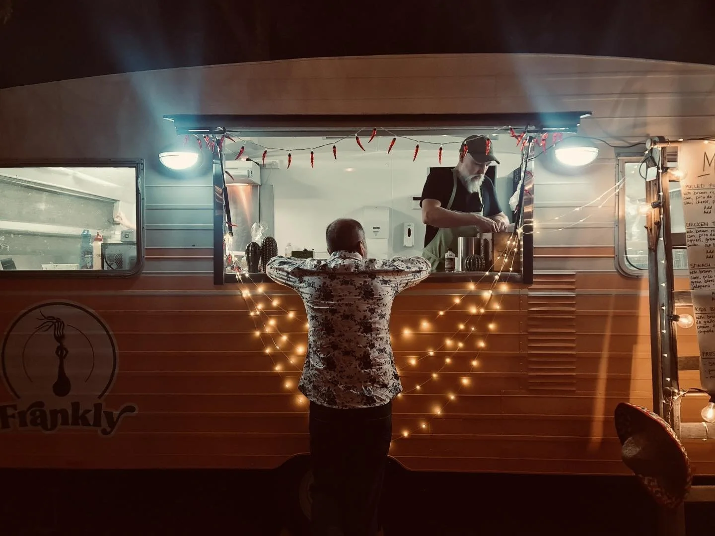 Man standing outside mexican food van ordering food.