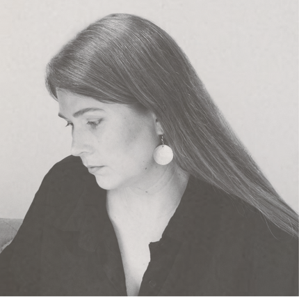 Nikki Blackford, co-principal of The Blackfjord, in black and white profile portrait focused on work, wearing a black blouse and mother of pearl earrings.