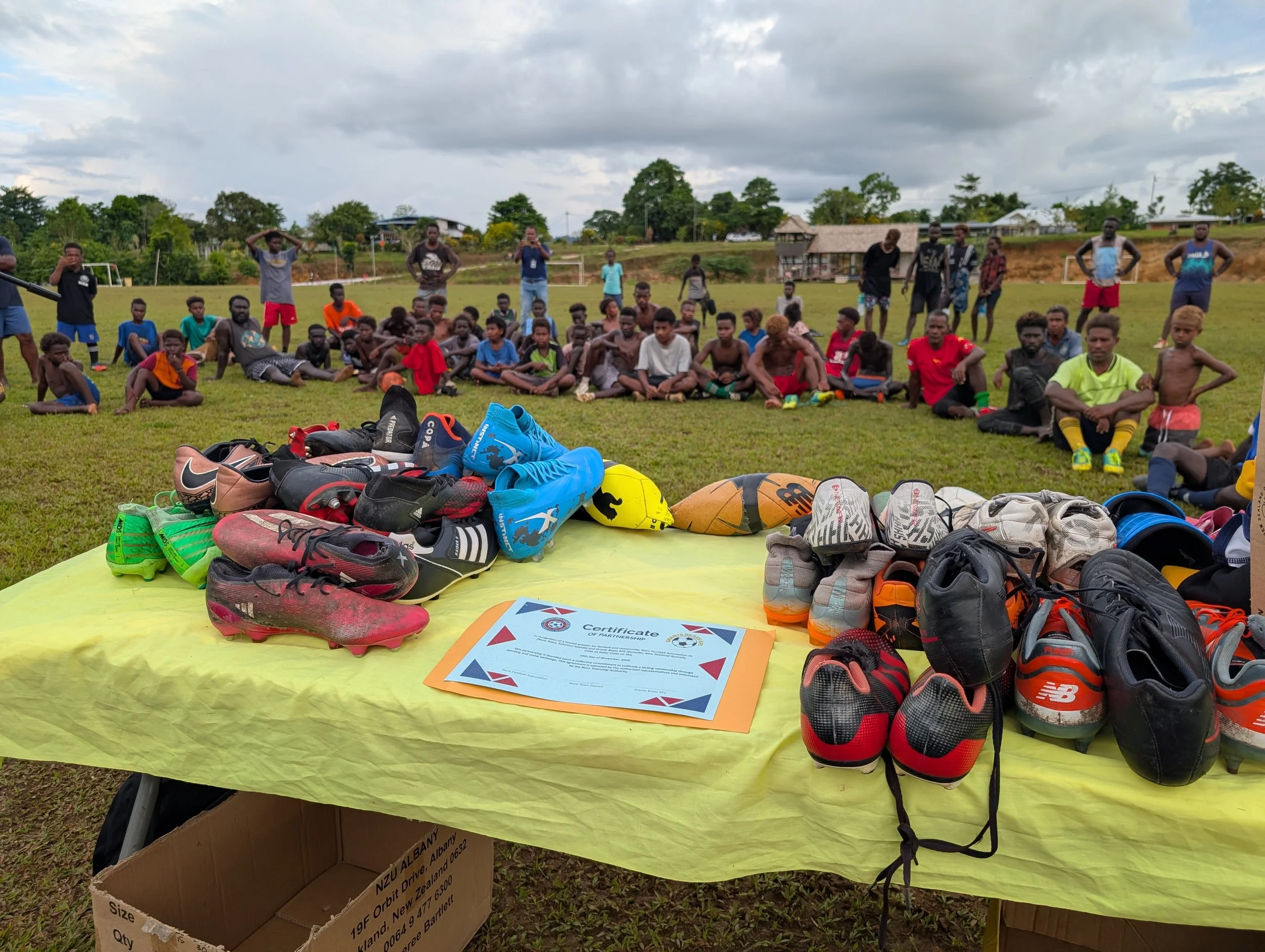 Noro Football club kids in the background, in the forefront - a table with a yellow table cloth and all the donated gear (boots, balls, etc).