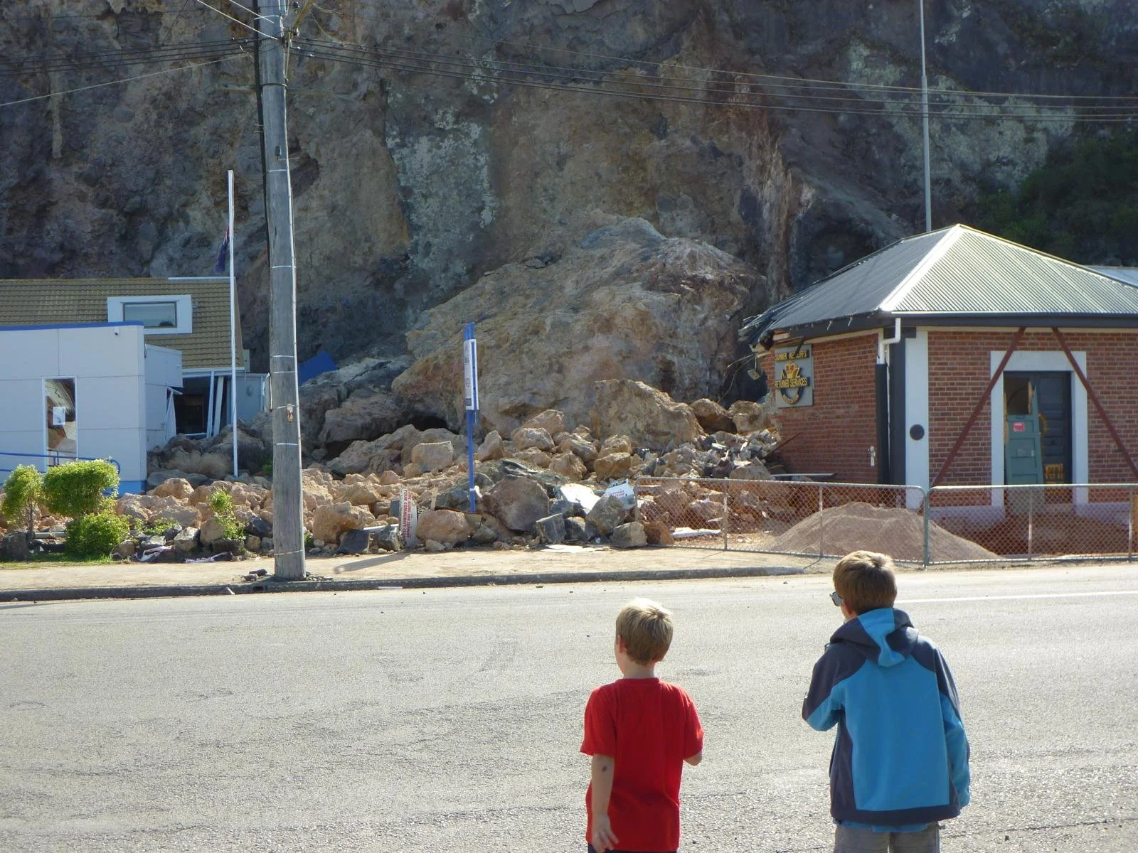 Two boys looking at the earthquake damage in their village, with their backs to camera.