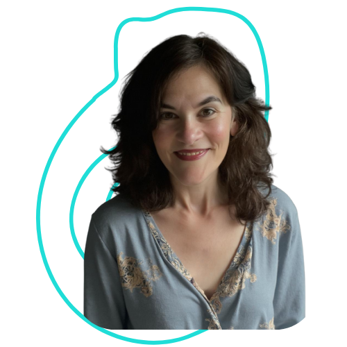 A woman with shoulder-length brown hair and light skin, smiling, wearing a light blue blouse with embroidery details.