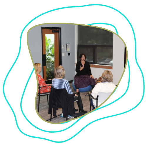 A woman leading a small group in a session inside a room with large windows and an open door.
