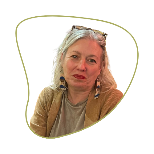 A woman with gray hair wearing earrings and a tan jacket, sitting against a light green background.