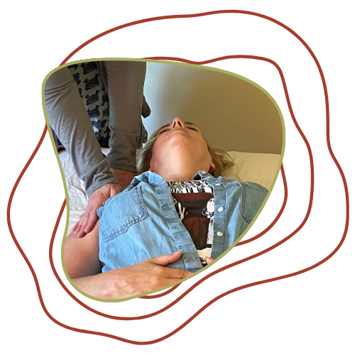 A woman lying on her back on a bed receiving a chiropractic adjustment from a practitioner.