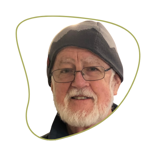 Close-up of an older man with a white beard and glasses, wearing a black and gray beanie hat, smiling.