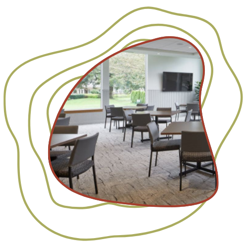 Empty conference or dining room with chairs and tables, large windows, and a television mounted on the wall.