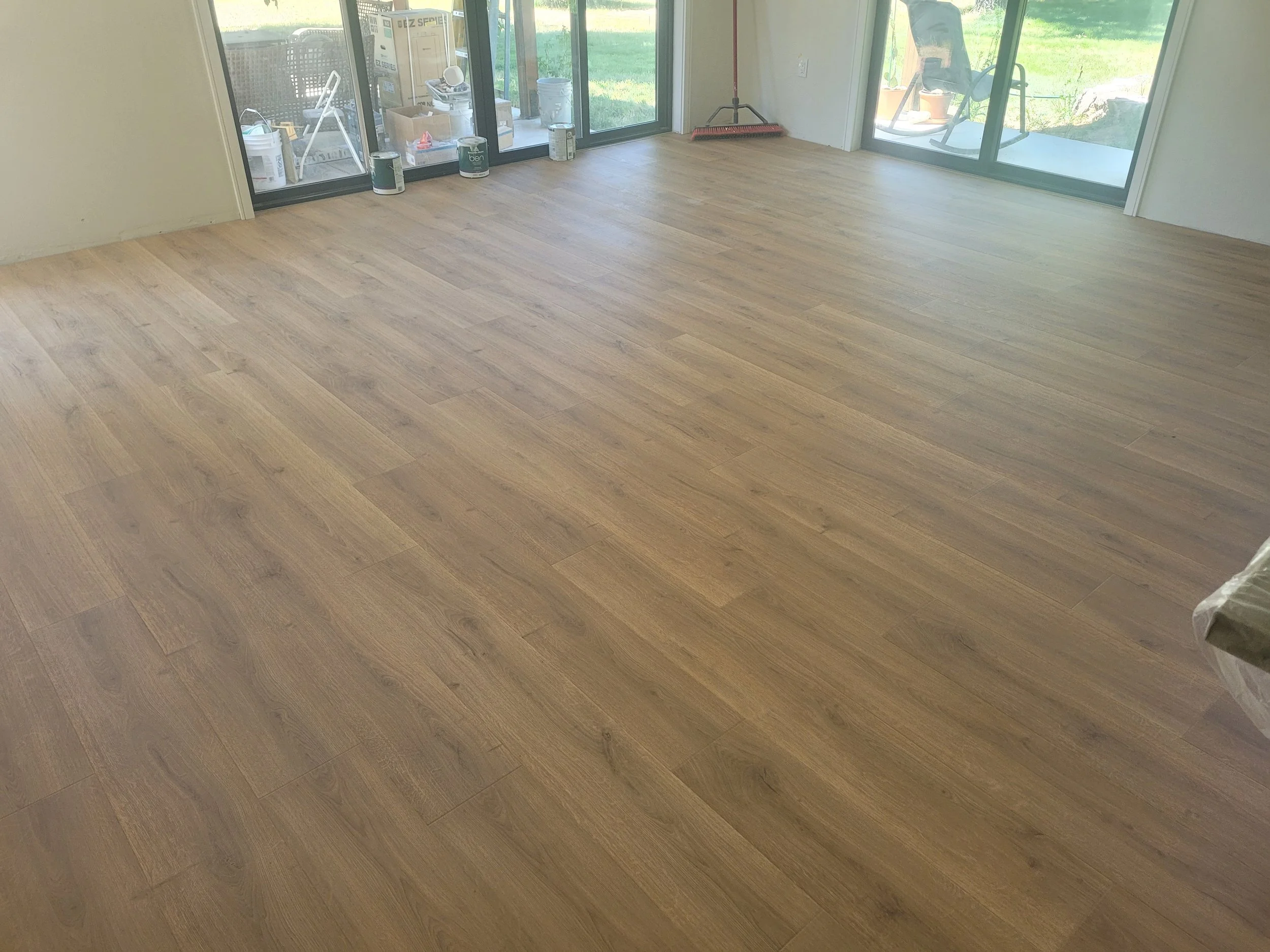 Room with newly installed wood laminate flooring and large sliding glass doors leading to outdoor patio.