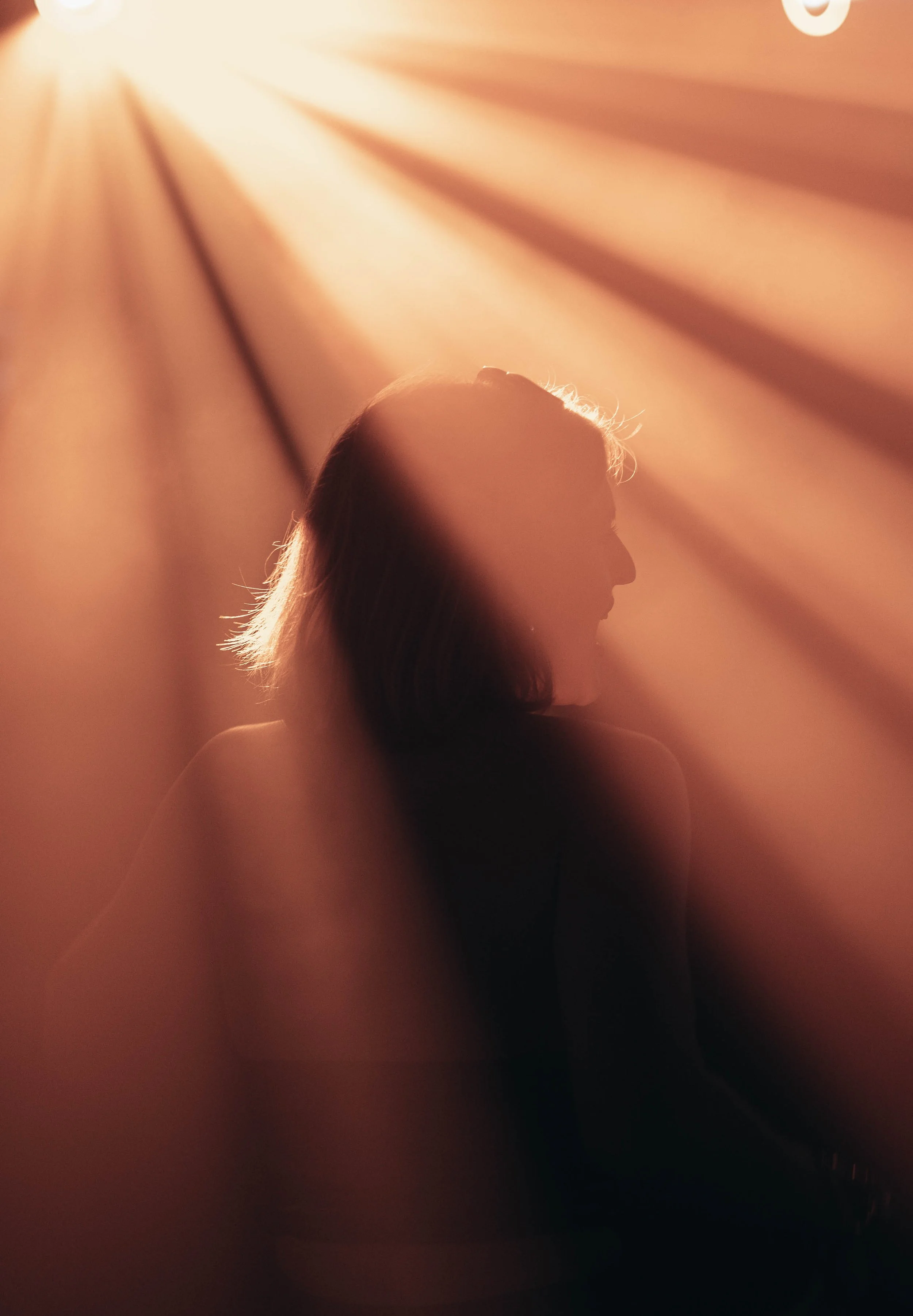 Silhouette of a woman with light rays shining down on her from above
