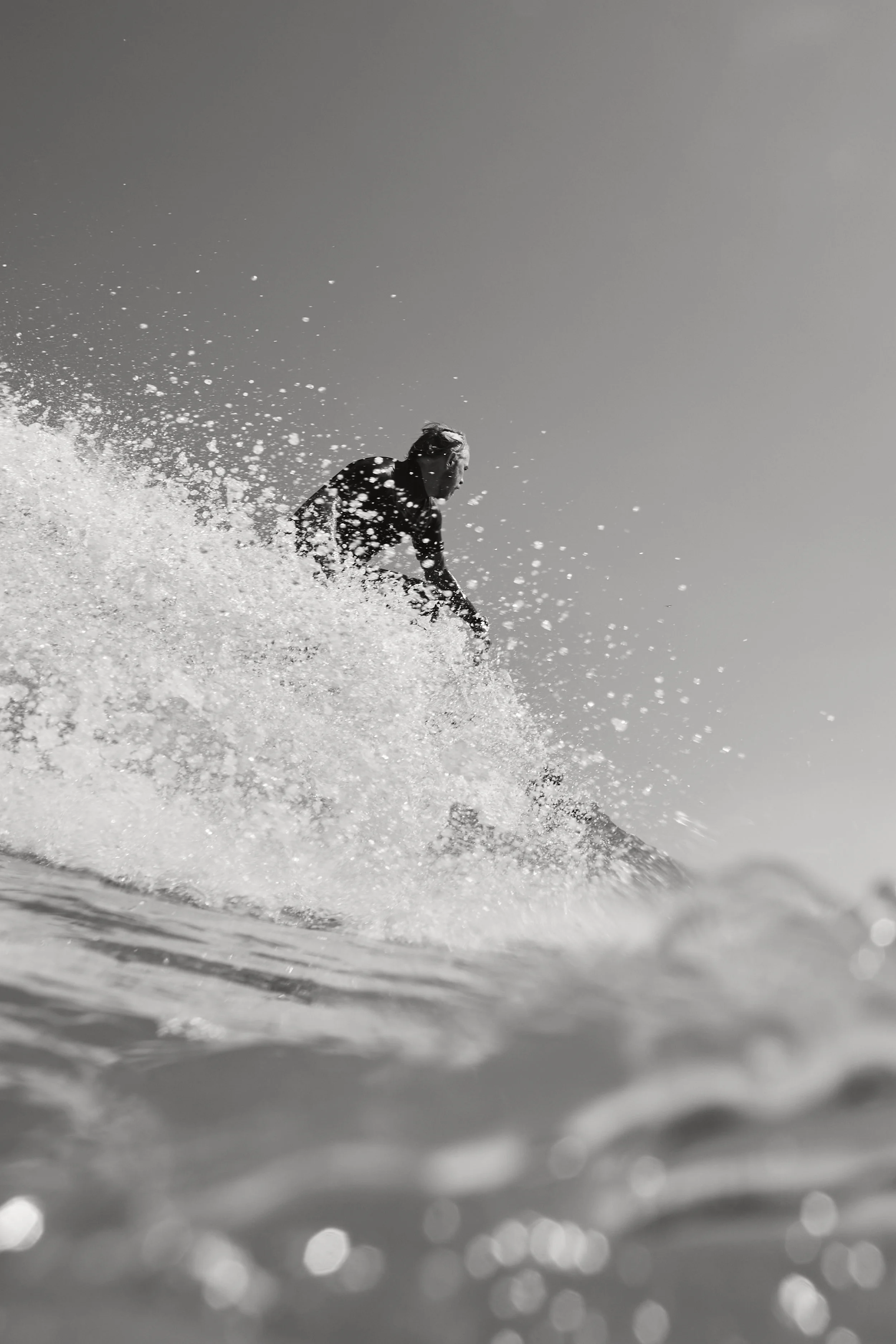 A person surfing on a wave in black and white.