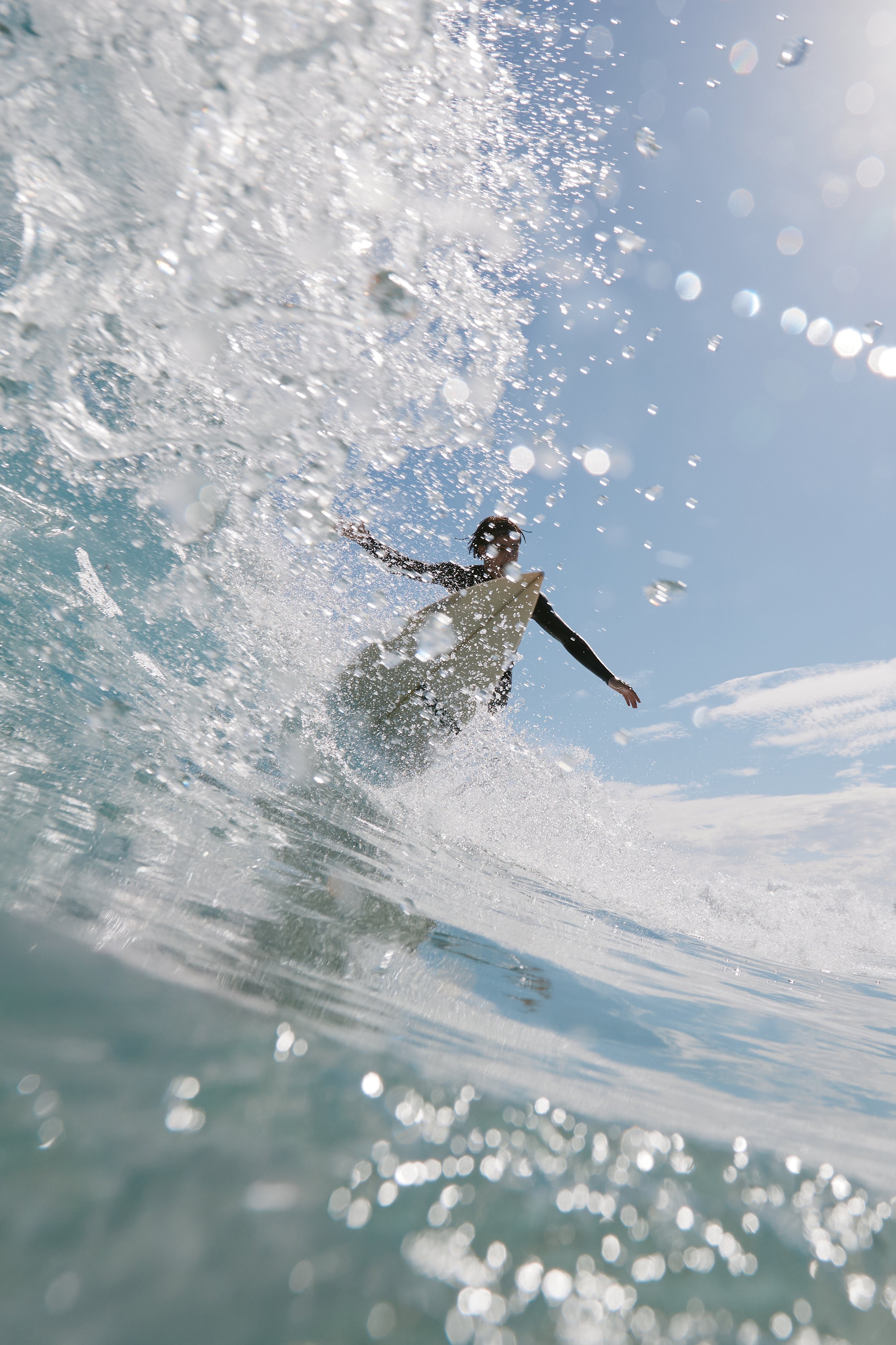 Surfer riding a wave in the ocean under a partly cloudy sky