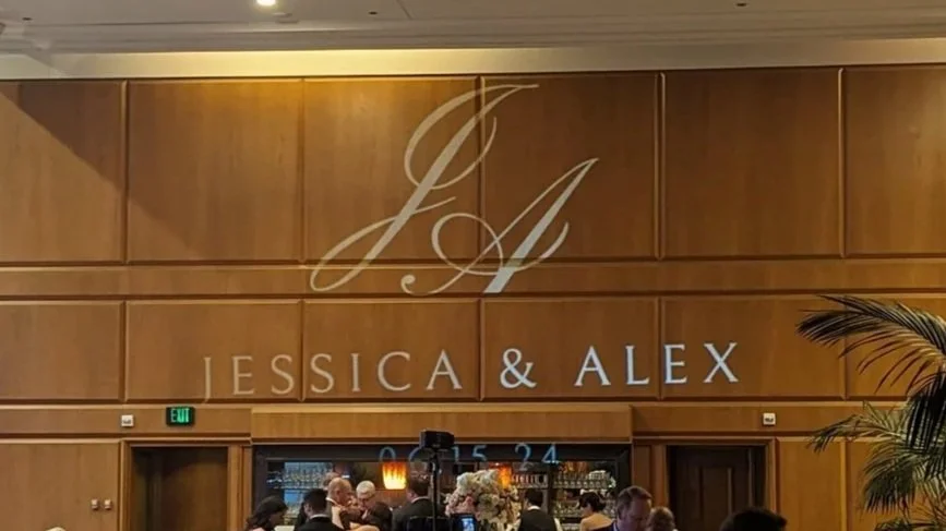 Wedding reception with a wooden wall background displaying the initials J and A, and the names Jessica and Alex.