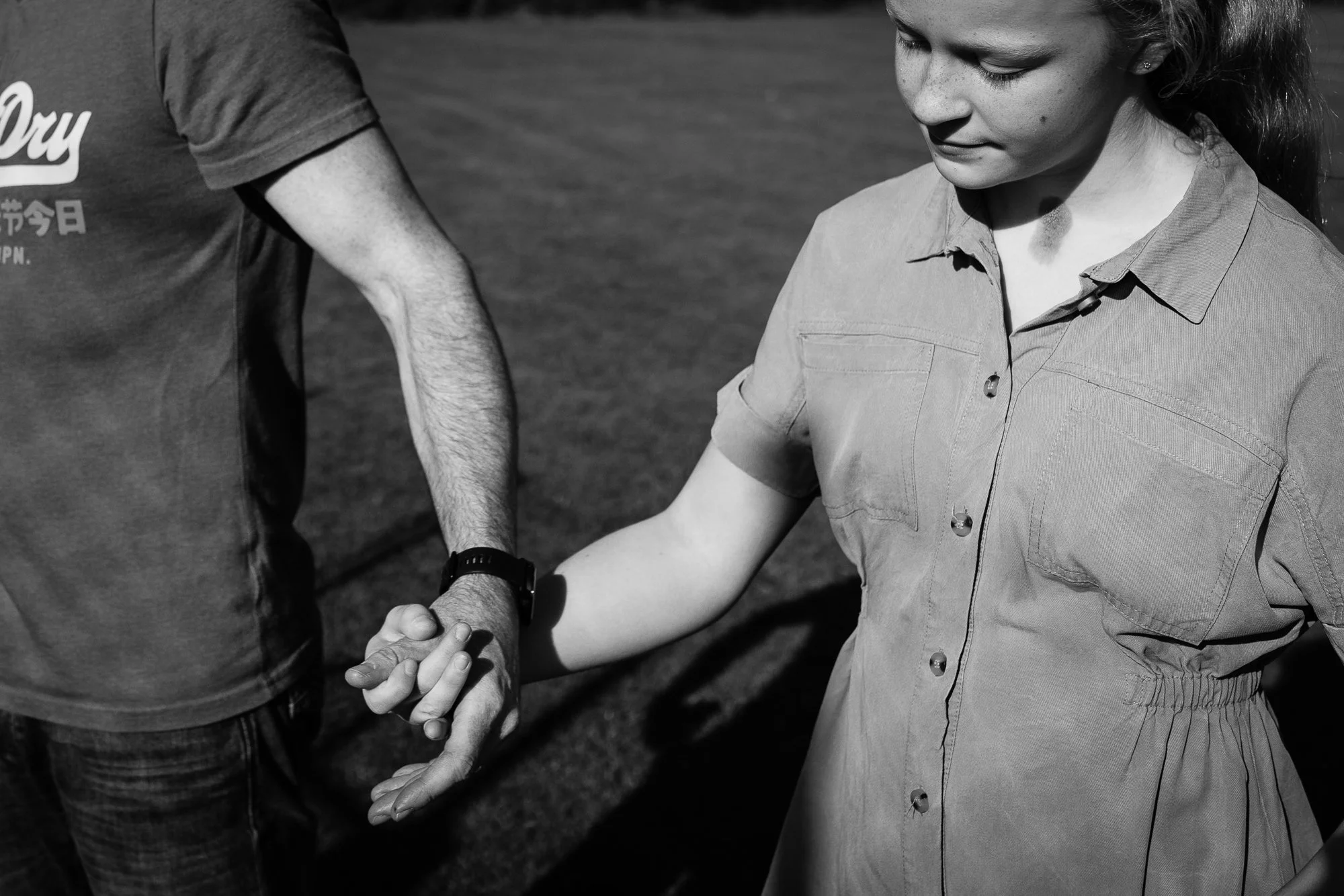 A man and woman holding hands outdoors in black and white.