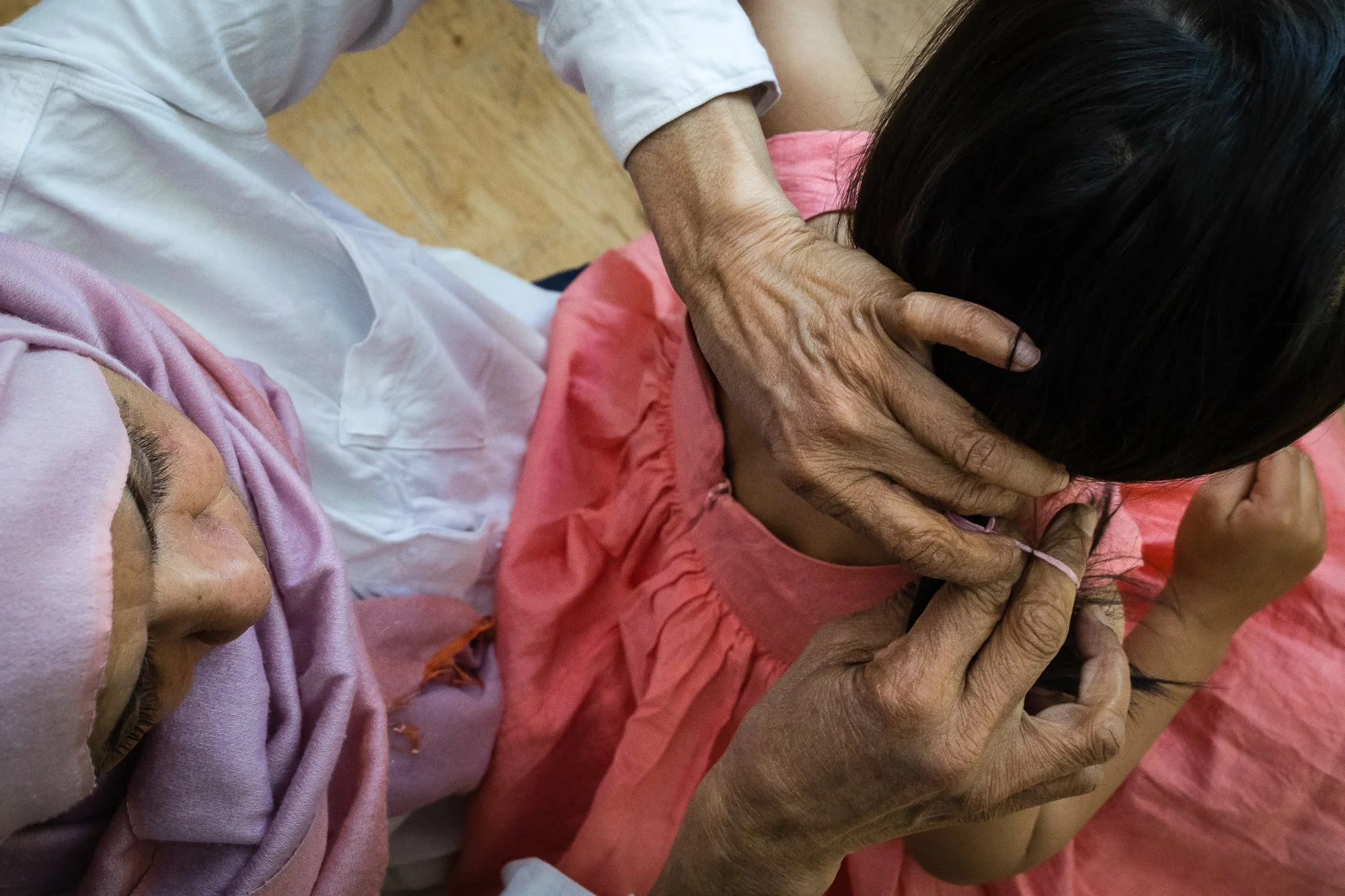 An older person administering acupuncture to a young girl on her neck and shoulder area.
