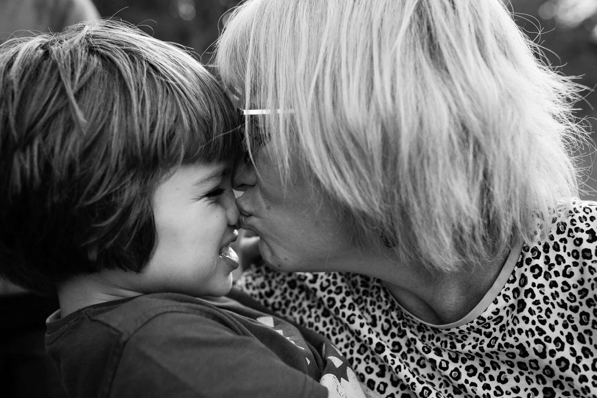 A young girl and an elderly woman are sharing an affectionate moment, noses touching and smiling while looking at each other.