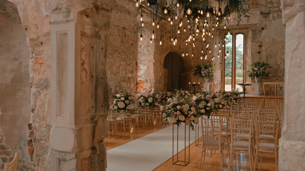 A ceremony space at Lulworth Castle in Dorset, chiavari chairs are lined up and a string quartet prepares to play