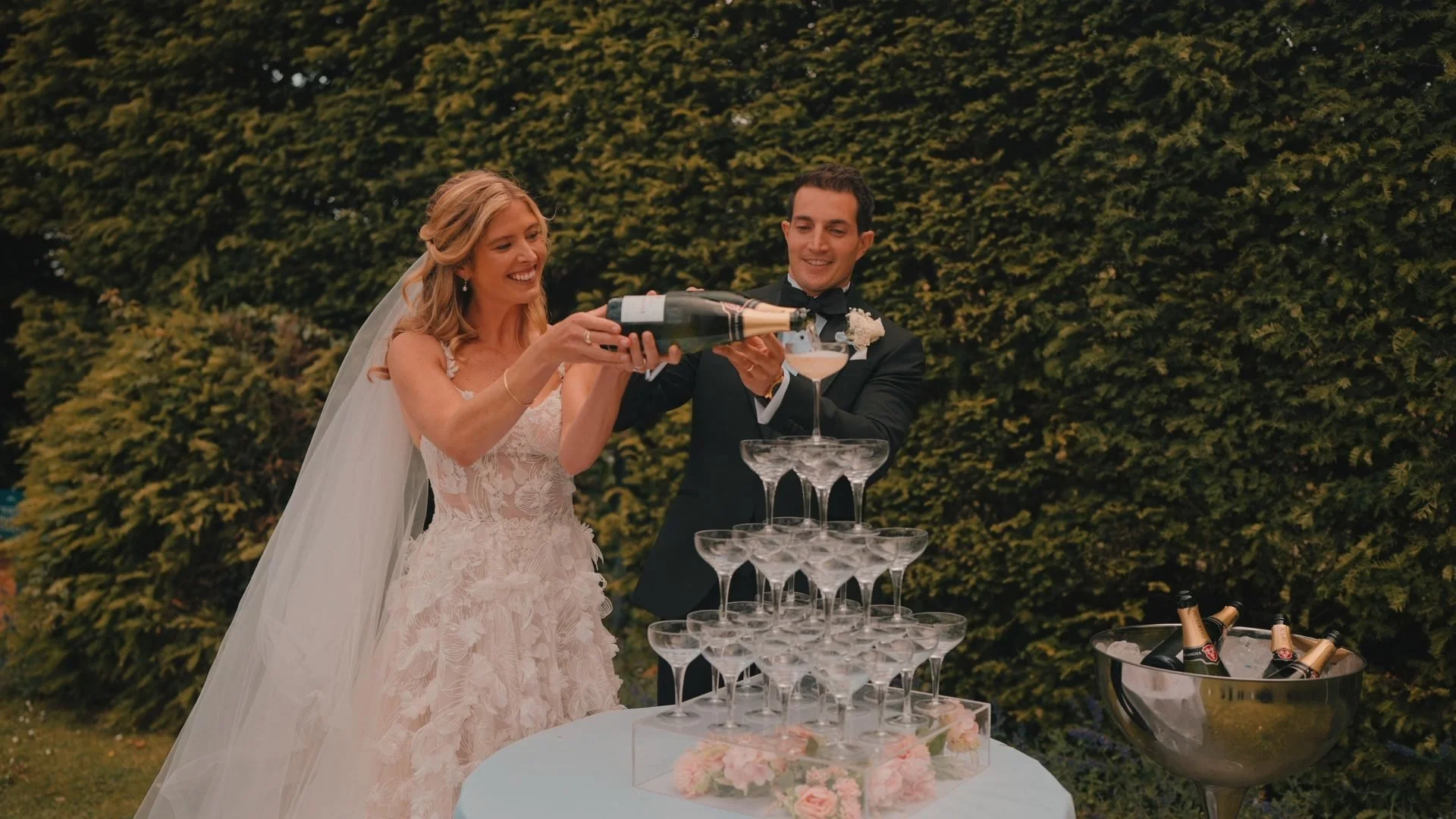 Wedding couple pouring a champagne tower at Lulworth Castle in Dorset, filmed by Spice Wedding Films