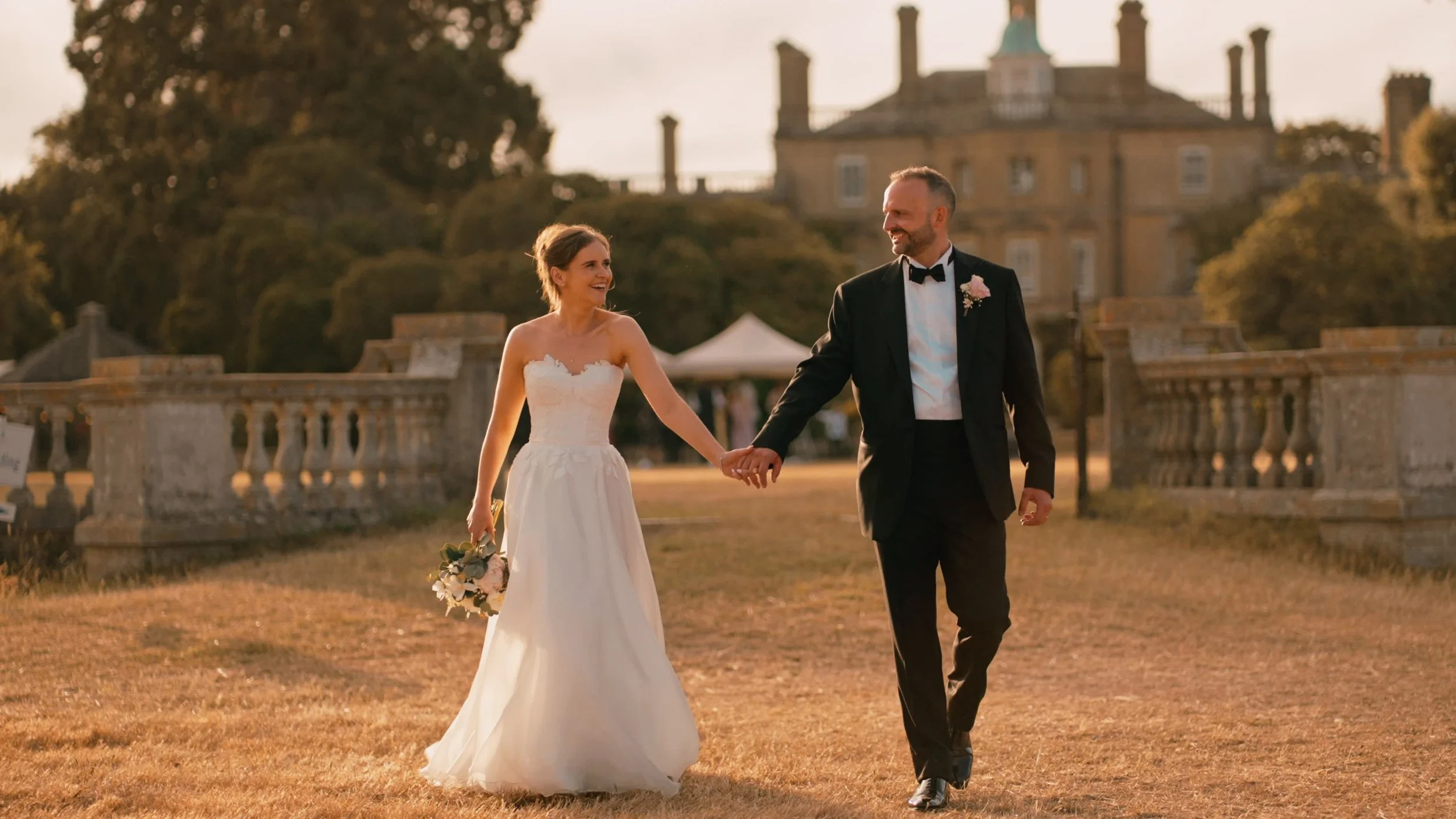 Pylwell Park wedding in Hampshire, a couple walks away from the house in golden sunset light