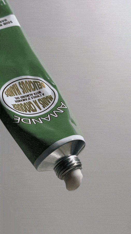 A green tube of Common Good brand hand and body cream with white lotion coming out of the opened nozzle.