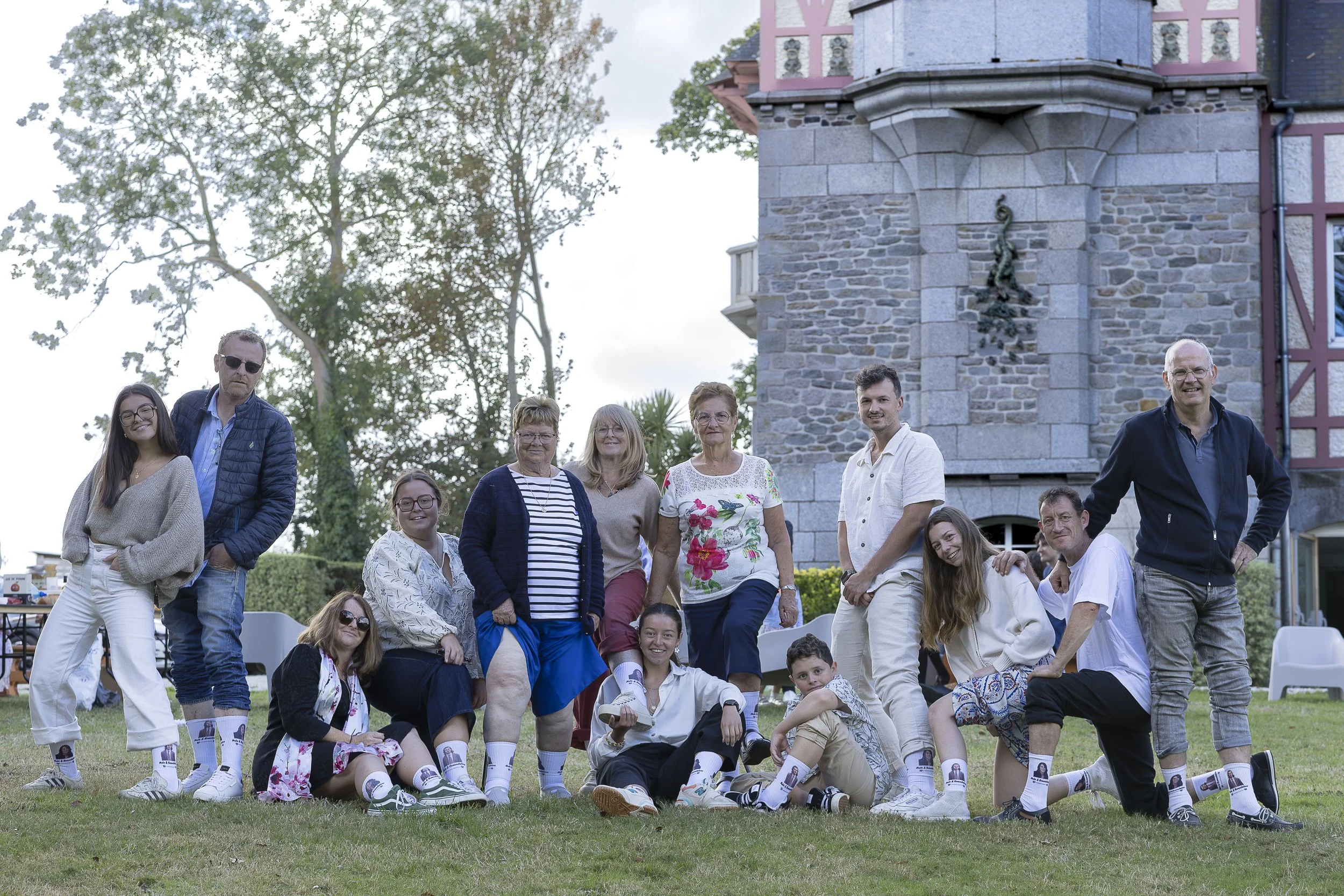 Groupe de personnes posant devant un manoir et une grande arbre, lors d'un mariage en plein air à la villa le clos à Saint-cast-le-guildo dans les côtes d’Armor en Bretagne.