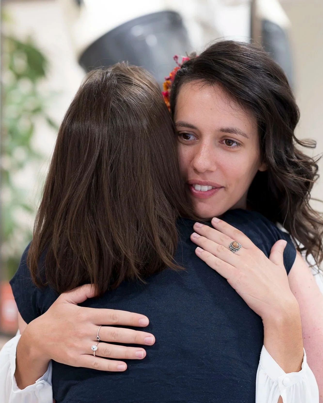 Deux femmes s'embrassent chaleureusement, l'une d'elles souriant doucement.