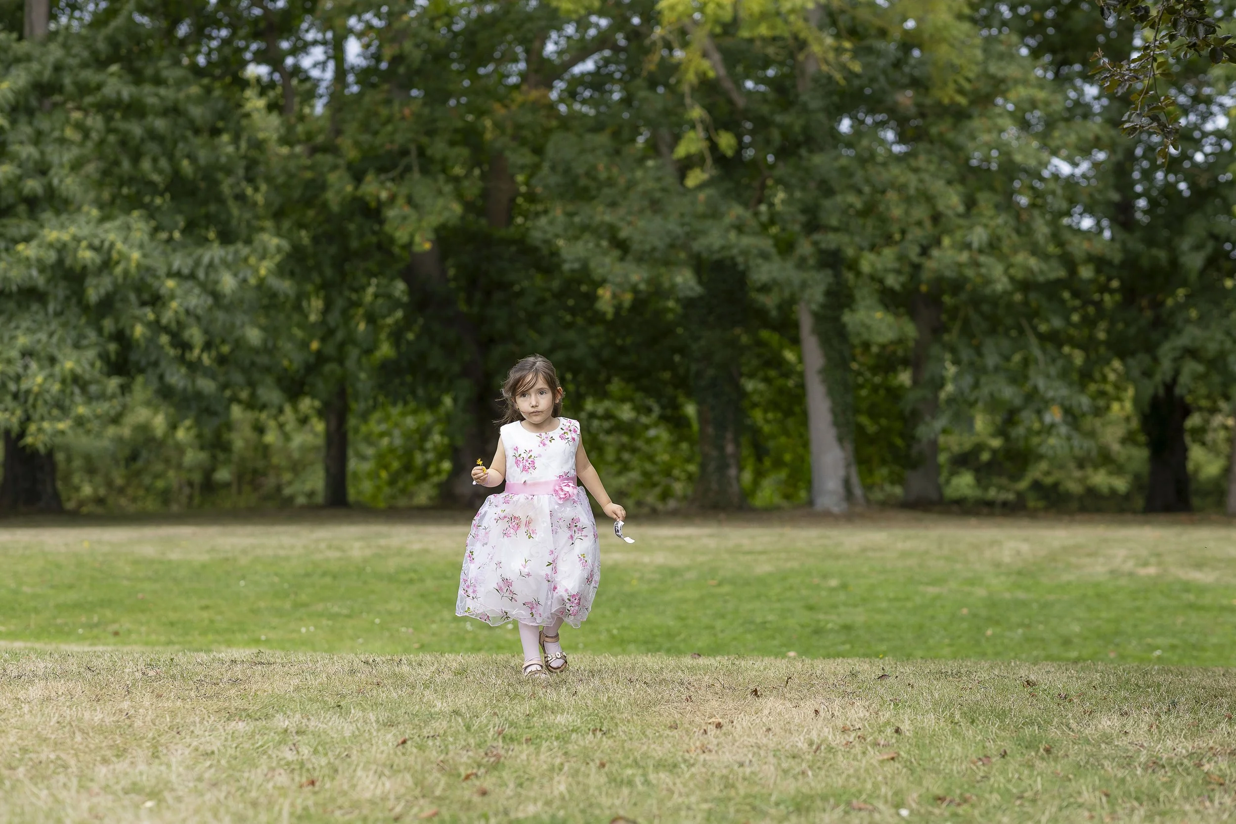 Jeune fille en robe blanche à fleurs pendant un mariage marchant sur une pelouse dans le parc à la villa le clos à Saint-cast-le-guildo dans les côtes d’Armor en Bretagne.