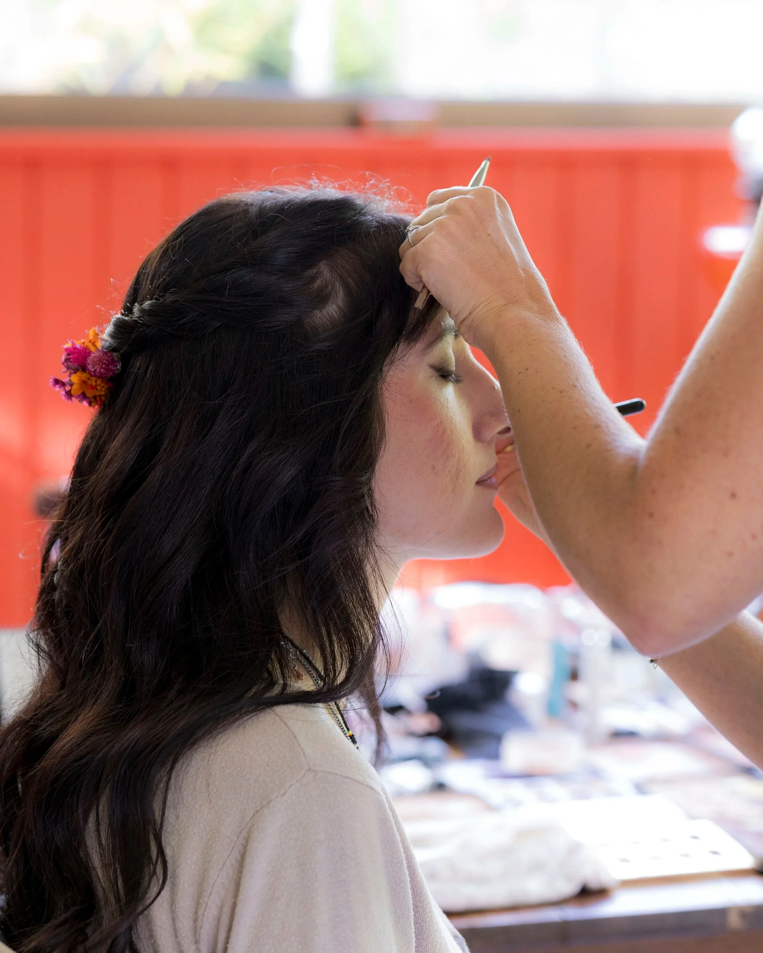 Une femme se fait maquiller les yeux par une artiste.