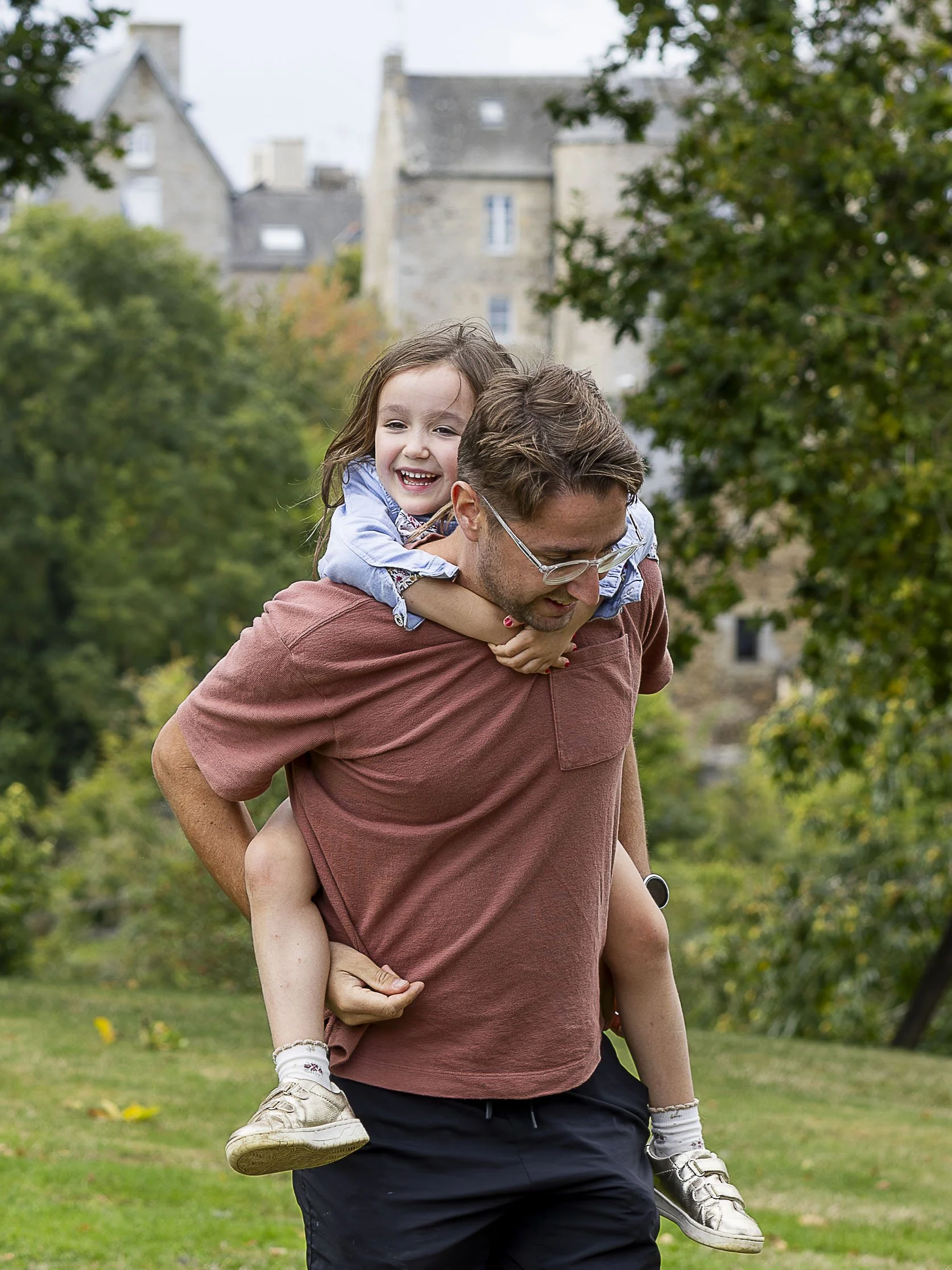 Un père portant une fille sur son dos pendant la cérémonie laïque d'un mariage dans le parc de la villa le clos à Saint-cast-le-guildo dans les côtes d’Armor en Bretagne.
