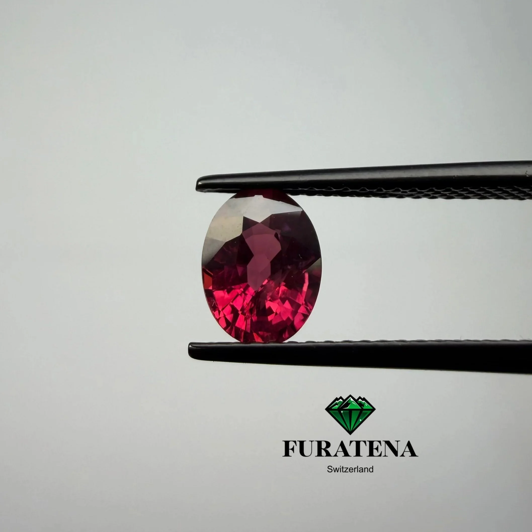 Logo de la marque Furaten à Genève, Suisse, avec une pierre précieuse rouge en forme de goutte en dessous, le texte 'FURATENA' en dessous et un petit logo en forme de diamant vert à côté.