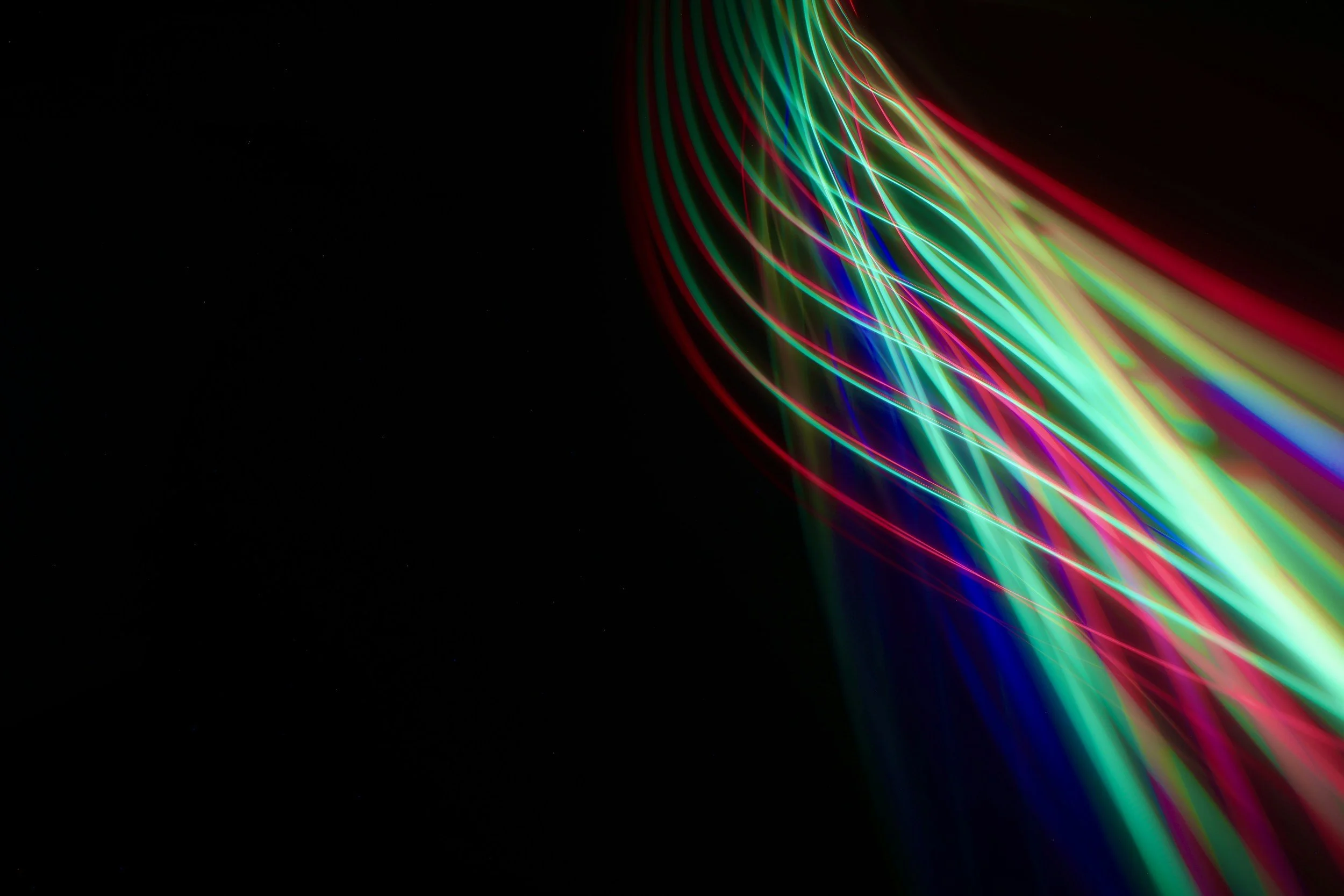 Colorful light trails in red, green, blue, and yellow on a dark background, creating a dynamic abstract pattern.