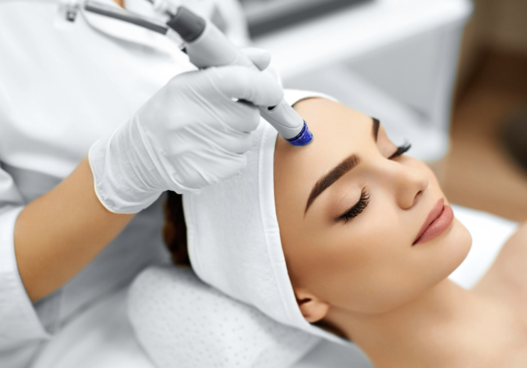 Woman receiving a facial treatment with a microdermabrasion device in a spa.