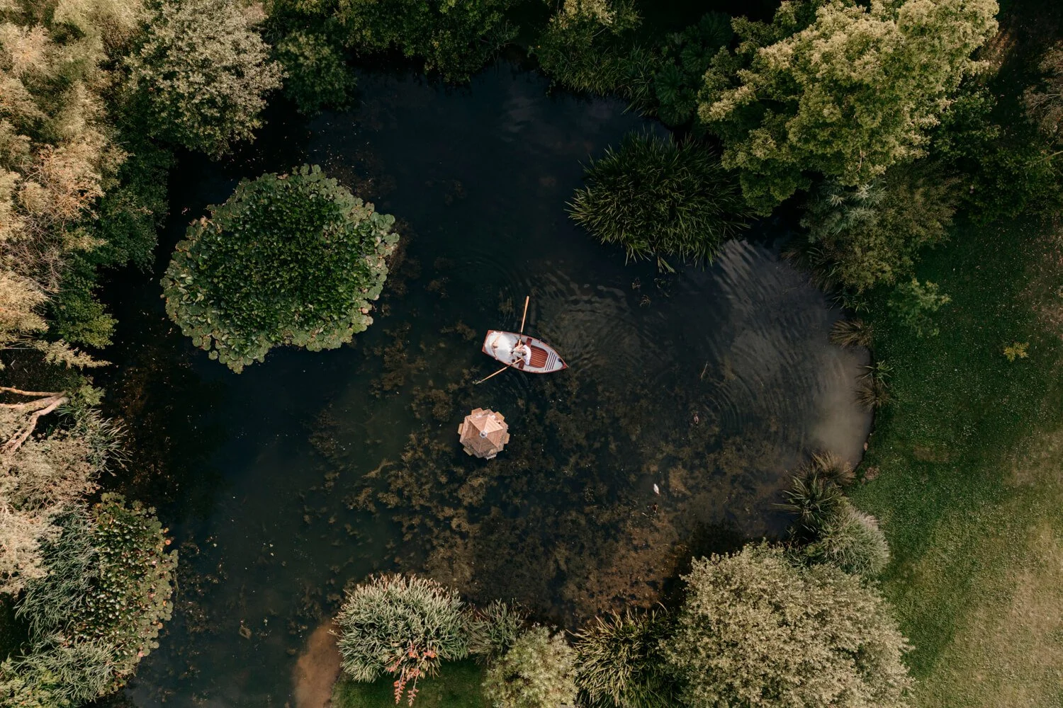 Drone photograph of a bride & groom at a wedding at Rudge Farm Dorset in a rowing boat on a lake.