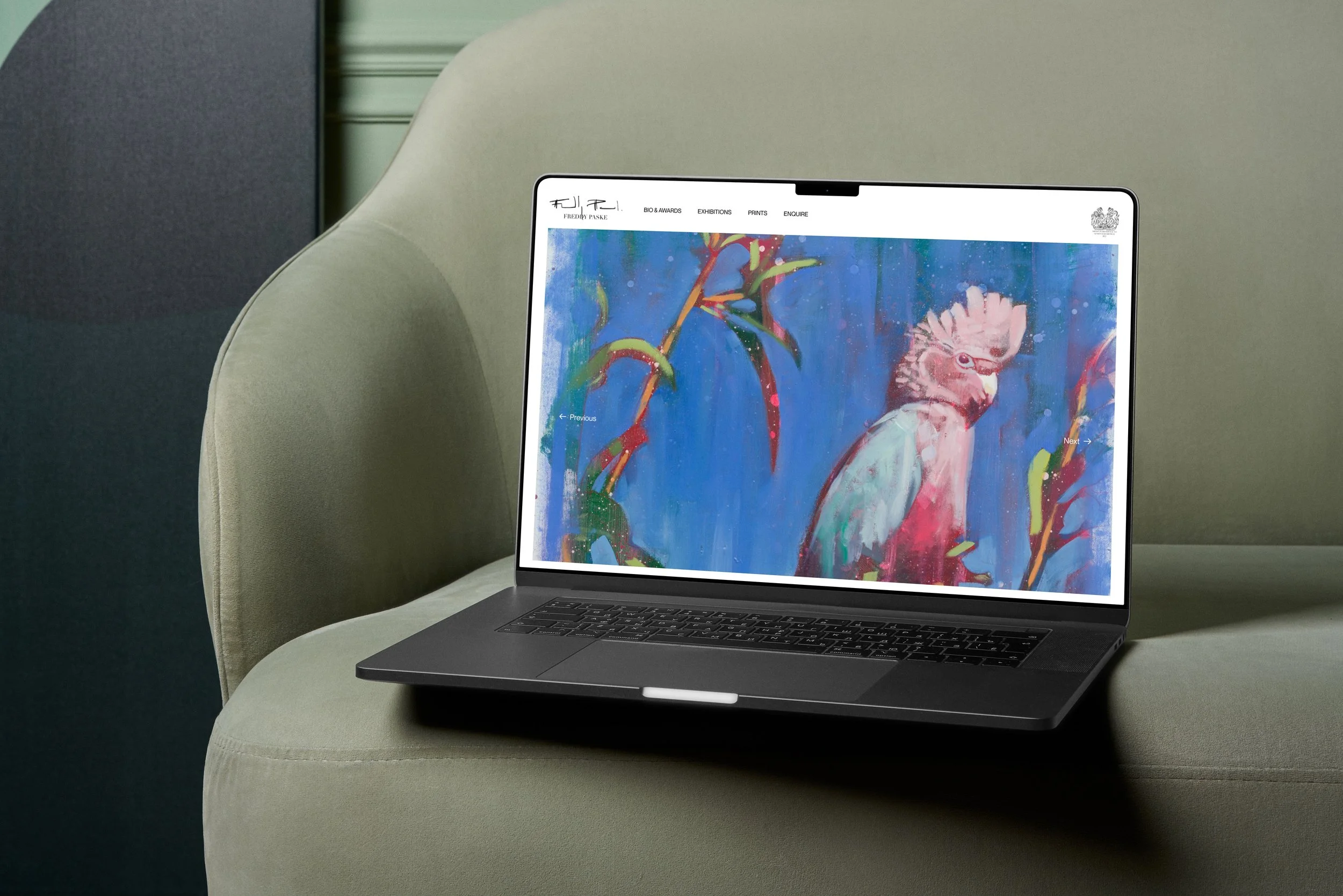 A laptop on an olive green couch displaying an abstract painting of a bird with pink and white feathers against a blue background with colorful leaves.