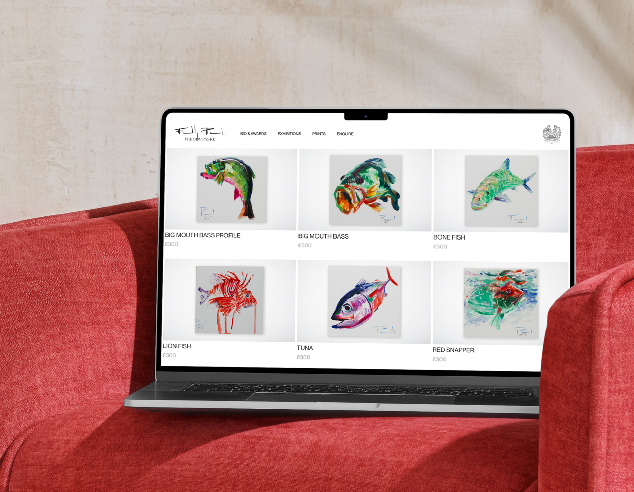 Laptop on red couch displaying an art website featuring colorful fish paintings with titles and prices.